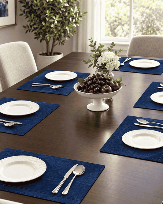 Blue upcycled denim table mats arranged on a dining table with plates and tableware.
