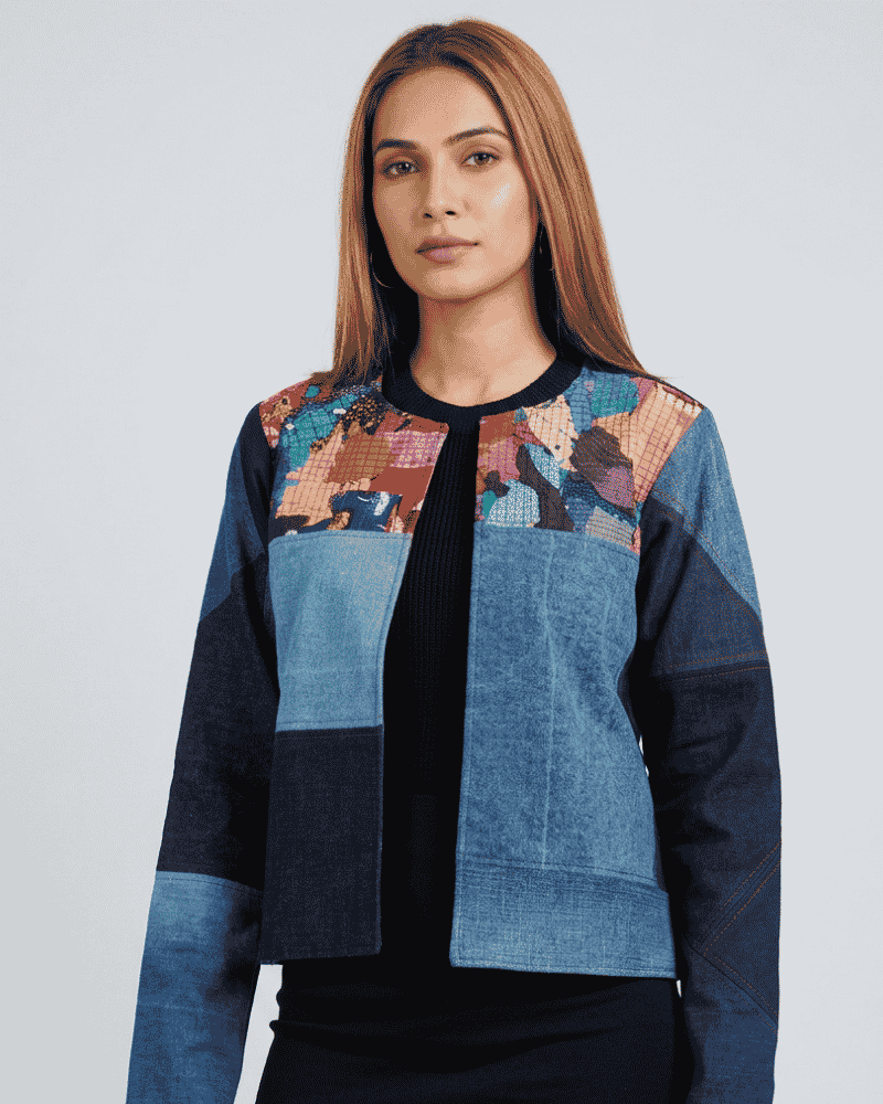 Woman standing in a blue geometric patchwork denim jacket with contrasting light blue and dark blue panels, Bunko Junko.
