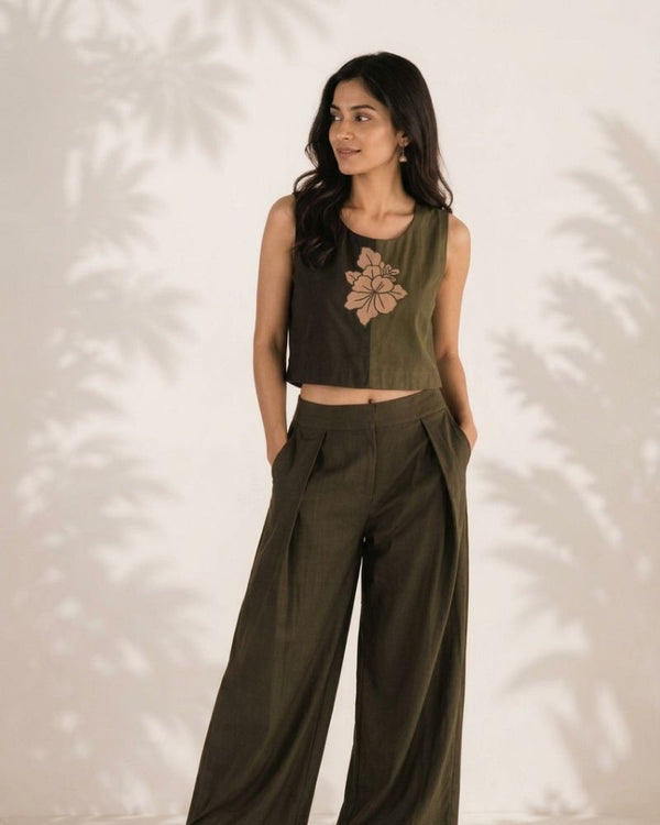 Full length view of a model wearing the Aroha floral crop top with dark wide leg trousers against a light backdrop.