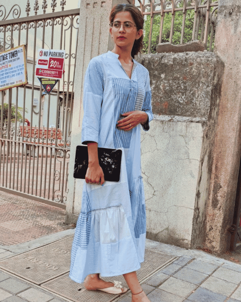 Woman wearing a light blue Fabric Finesse dress with a black clutch
