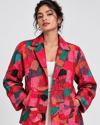 Model wearing a pink and red jacket made from patchwork style fabric.
