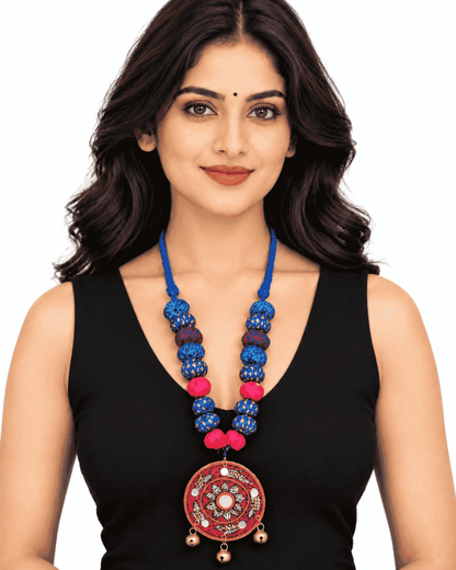 Woman wearing a blue beaded statement necklace with a circular artistic pendant and a black sleeveless top.
