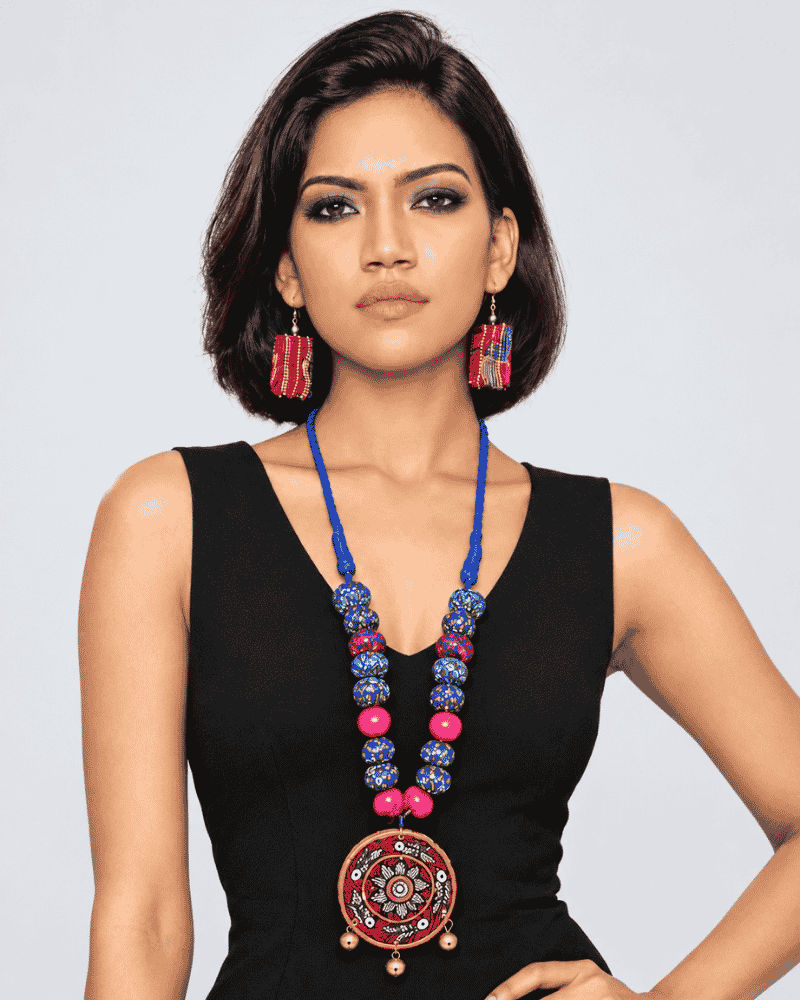 Woman wearing a handcrafted Wearable Art Necklace with blue beads and a circular Madhubani style pendant.
